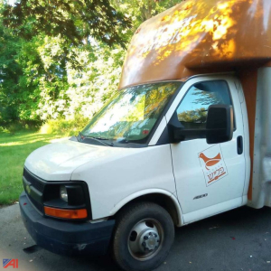Cargo van-style food truck with white cab and brown food truck body, side view showing logo on passenger door, Chevrolet Express 3500 badge visible.