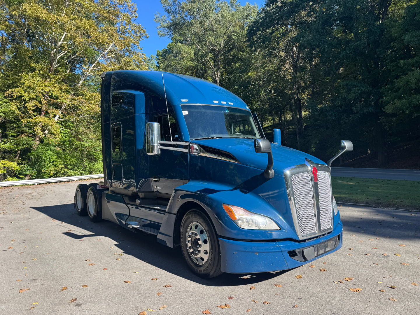 Kenworth T680 semi-truck in blue showing front grille and side view with sleeper cab.