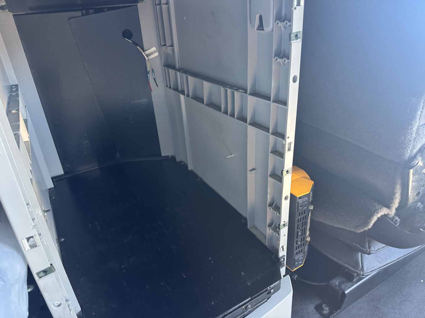 Kenworth T680 cab interior showing cargo area with black floor, side panel, and yellow tool or battery unit in doorway.