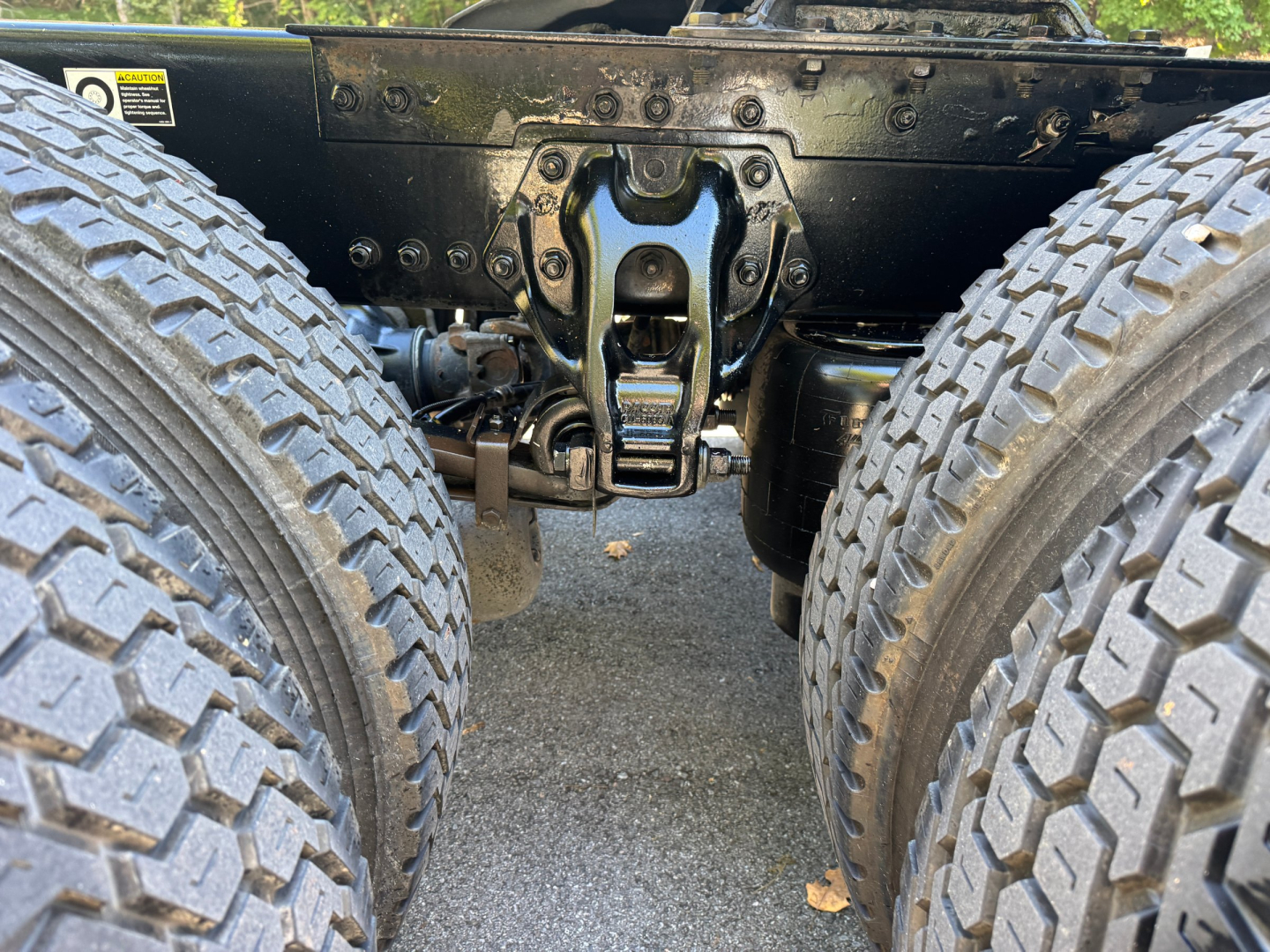 Kenworth T680 chassis with tandem rear axles and fifth wheel, close-up view of suspension and drivetrain components between dual tires.