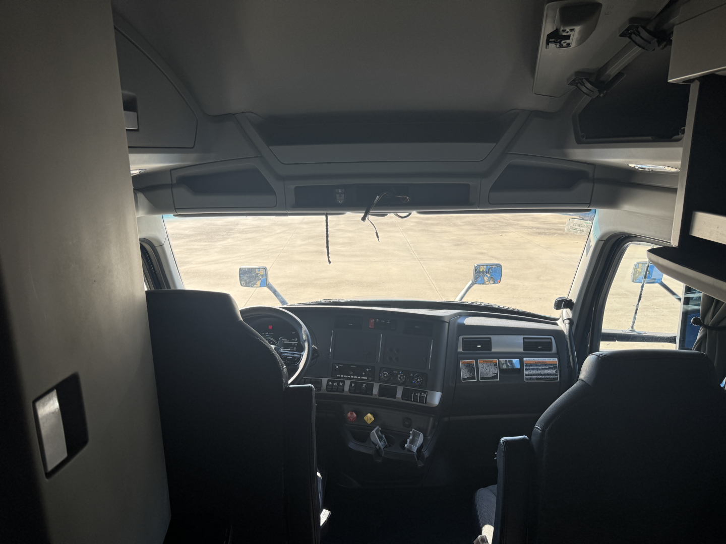 Kenworth T680 truck interior cabin view from driver seat showing dashboard and steering wheel.