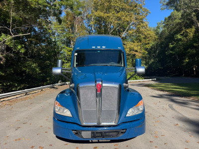 Blue 2024 Kenworth T680 conventional sleeper truck front view with grille, headlights, and large windshield.