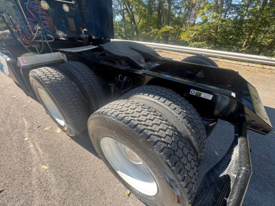Kenworth T680 truck chassis showing rear dual axles and fifth wheel area with tires and suspension visible under a blue cab