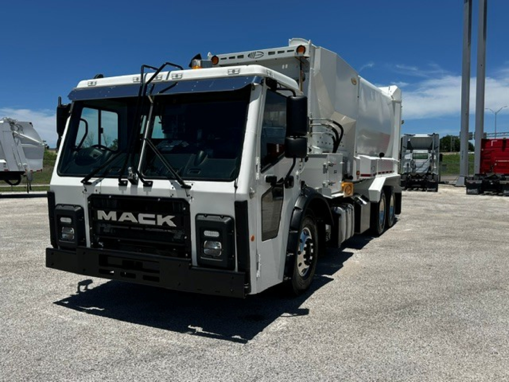 Front view of a white Mack LR64 refuse truck with black grille and large windshield. visible text on grille reads 'MACK'.