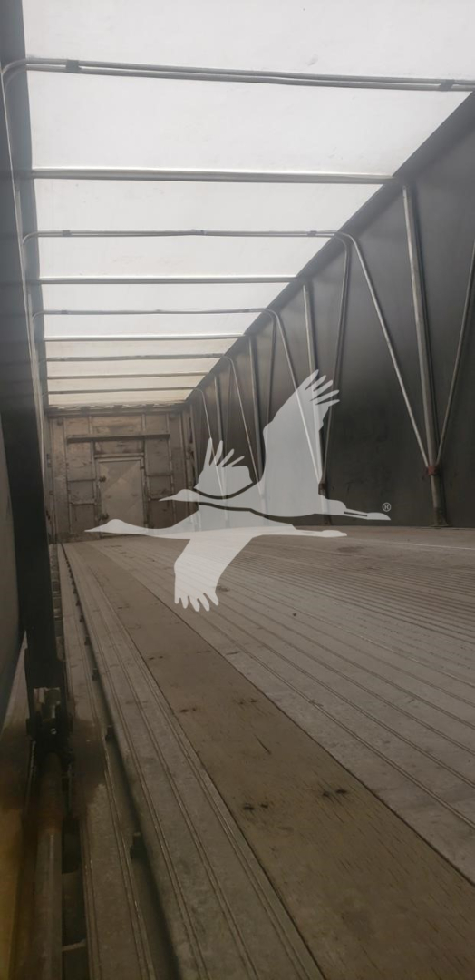 Trailer interior showing metal side walls and ribbed floor of a curtainside trailer