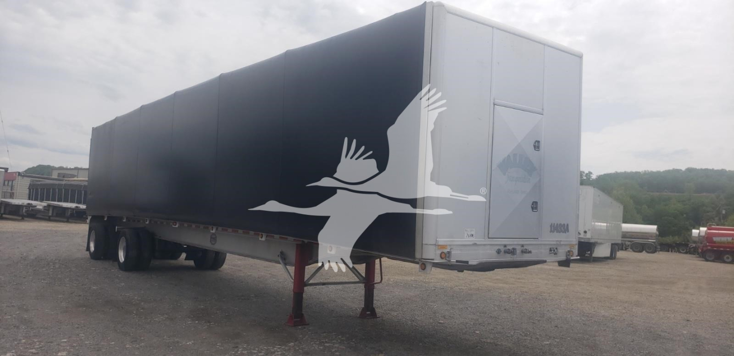 Trailer side view showing a black curtainside with white graphic of flying cranes and the rear end with light gray hatch; dual rear axles visible.