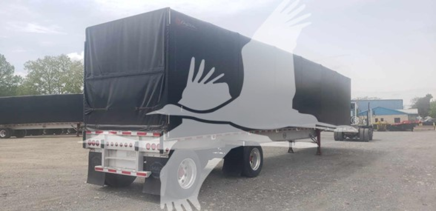 Curtainside trailer with black cover and white logo on side showing stylized bird; rear view with bumper and taillights visible.