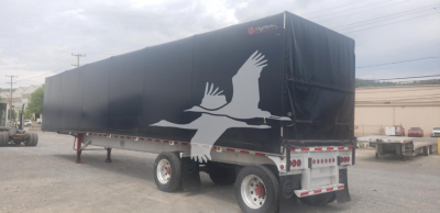 Curtainside trailer showing black tarp with white bird graphic and rear LED lights, side view.