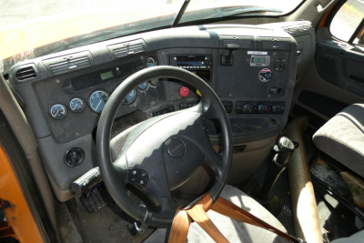 Truck cab interior of a Freightliner Cascadia 125 featuring steering wheel, dashboard gauges, and control panel.