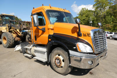Freightliner Cascadia 125 daycab truck in orange and black, side view showing cab and front grille, VIN tag and stock number not visible.