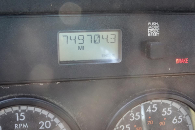 Dashboard of a Freightliner Cascadia showing an odometer/screen reading 749,7043 miles? The image includes gauge dials, a PUSk/MODE button, BRAKE indicator, and engine display area.