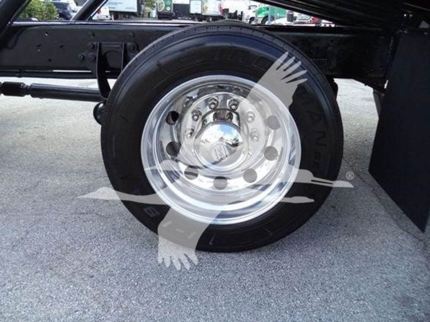 Truck wheel and tire on a 2019 International Durastar 4300 rollback chassis showing shiny steel hub and black wheel well.