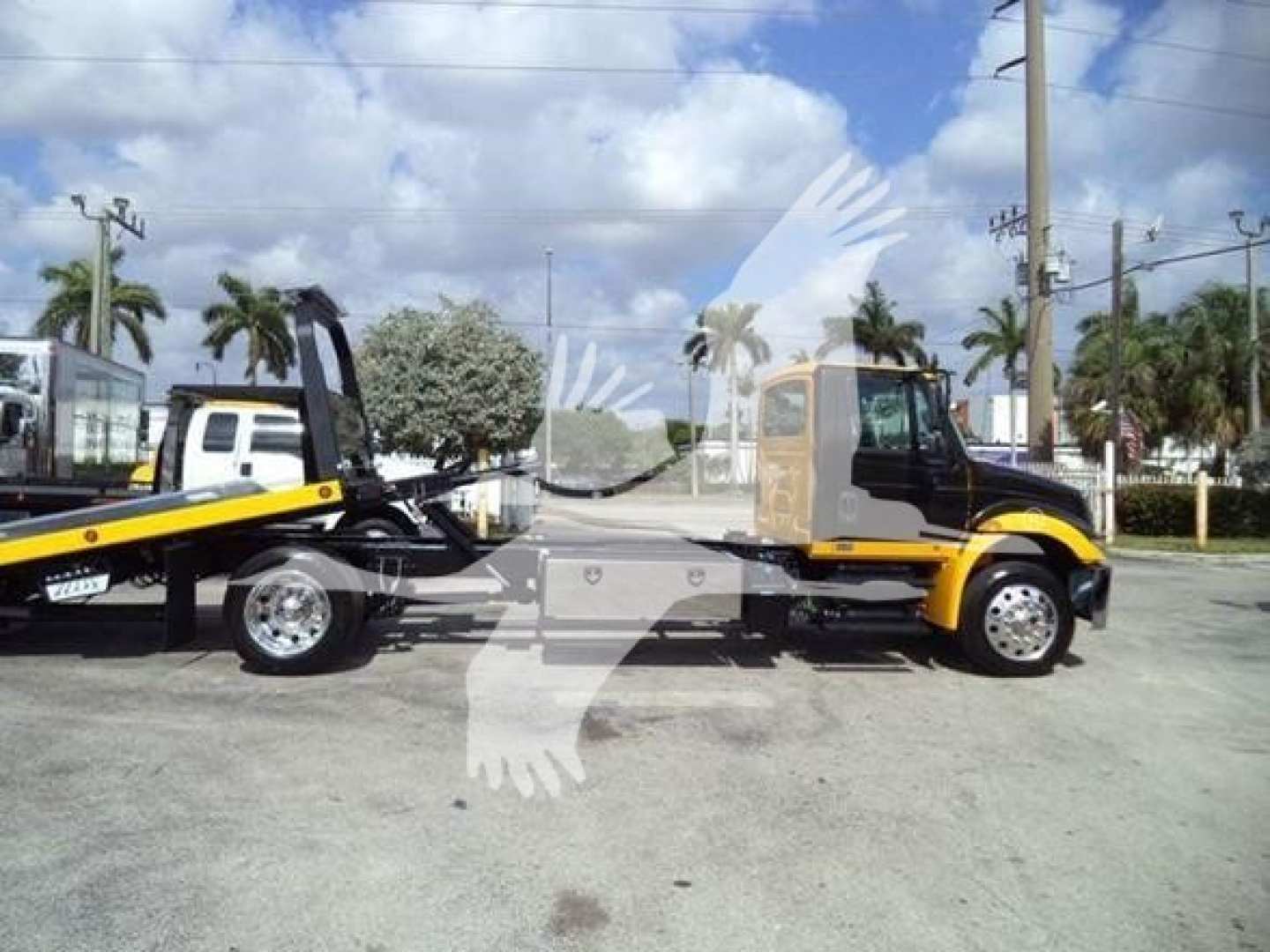 International Durastar 4300 rollback truck in yard showing cab and trailer, VIN 1HTMMMML0KH382488, stock T82488, two-tone yellow and black.