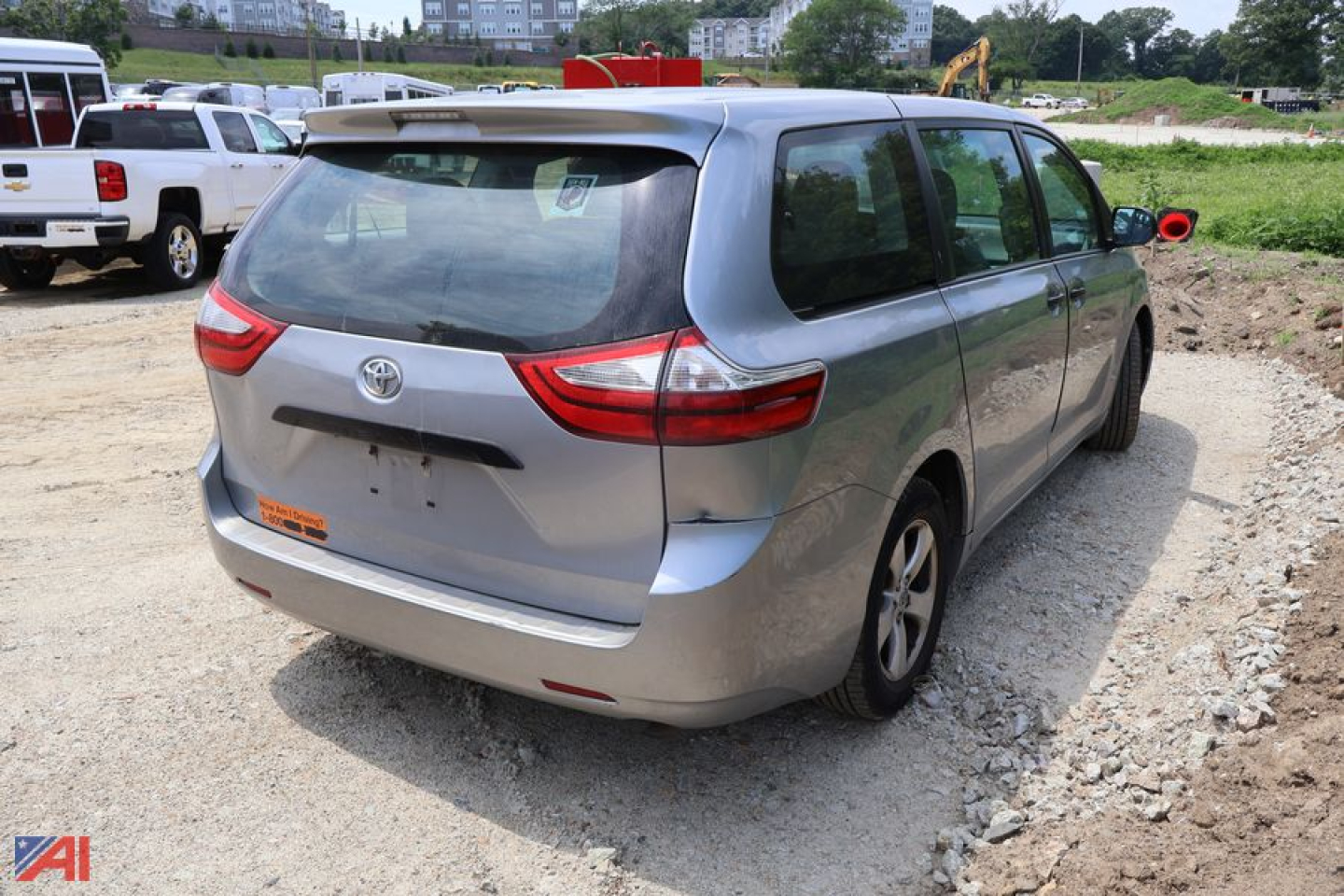 Rear three-quarter view of a light blue 2016 Toyota Sienna minivan in a gravel lot.