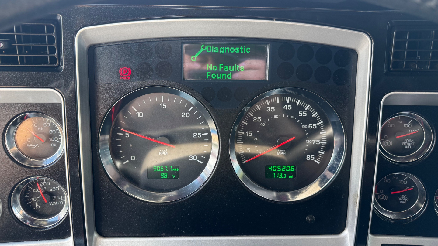 Kenworth W900 gauge cluster showing diagnostic screen with No Faults Found and various metric gauges.