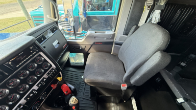 Kenworth W900 truck cab interior showing driver seat and dashboard with multiple gauges and controls.