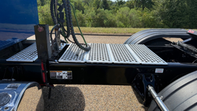 Kenworth W900 sleeper-conventional truck chassis showing platform and rear cab area with hydraulic lines and connection plate.