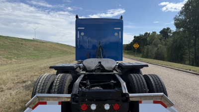 Kenworth W900 truck rear view showing fifth wheel, dual rear axles, and mud flaps.