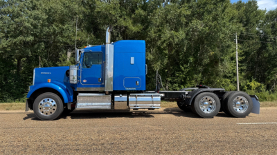 Kenworth W900 truck side view with blue cab, chrome exhaust stacks, and rear axle assembly.