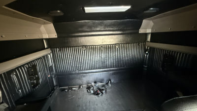 Kenworth W900 truck cargo area showing rear sleeper alcove and metal ribbed walls with harnesses on floor.