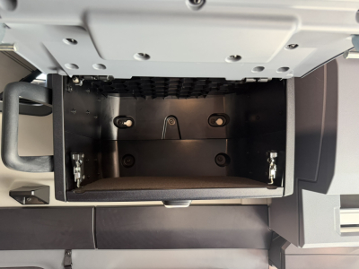 Concealed center console area of a new 2027 Mack PR64T76H sleeper truck showing an empty under-dash storage compartment with mounting points.
