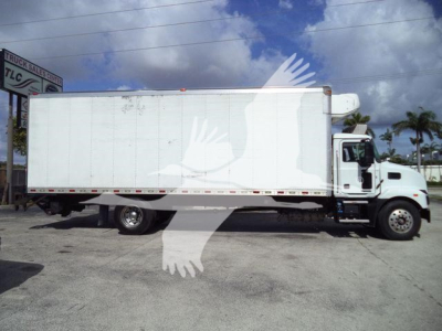 Truck side view showing a white 2023 Mack MD6 refrigerated box truck with a cab-over-engine design, stock number 268303RFM, and a large rectangular cargo box.