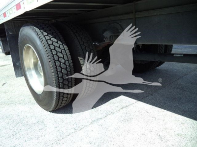 Rear wheel of a Mack MD6 truck with dual tires under a refrigerated trailer; stock number 268303RFM mentioned in listing context.