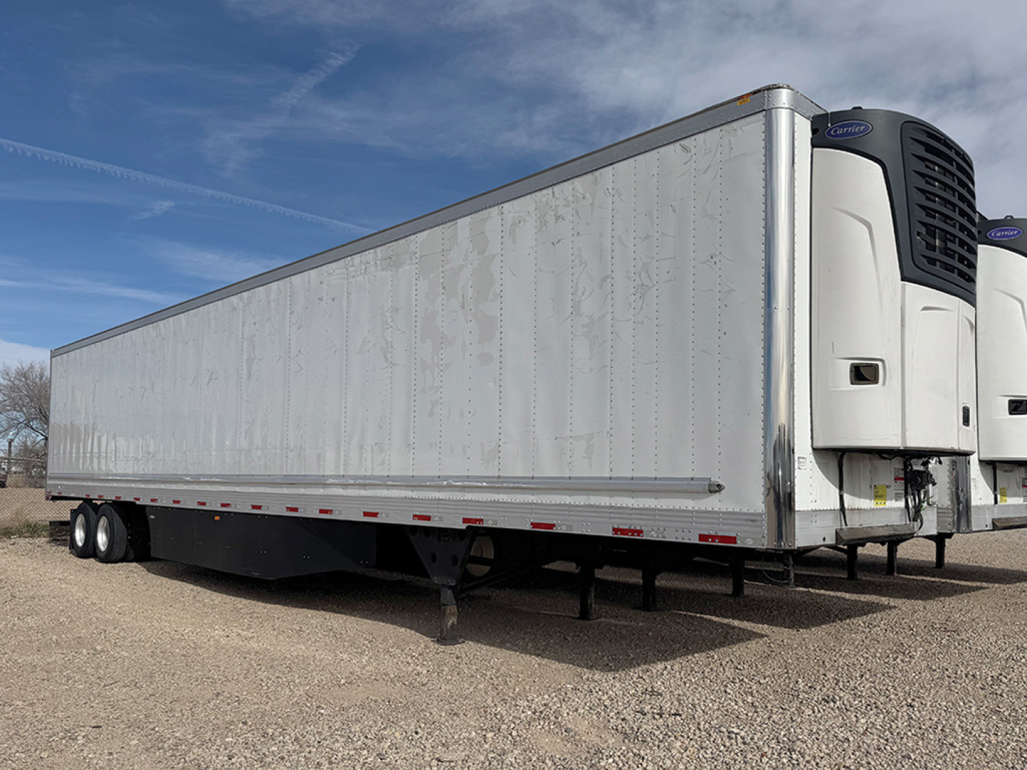Utility 3000R trailer with reefer unit at the front showing plain silver side panels and a blue sky; side view highlighting the refrigeration unit at the front.