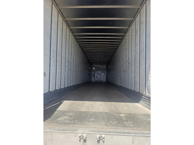 Trailer interior showing long enclosed cargo space with metal ribbed walls and ceiling; empty floor and rear opening.