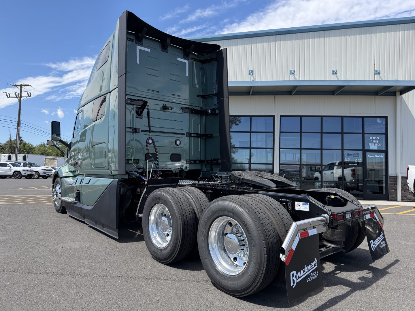 Volvo VNL64T860 cab and chassis rear view showing fifth wheel and dual rear axles, green exterior, sleeper configuration, with chrome wheels and mud flaps.
