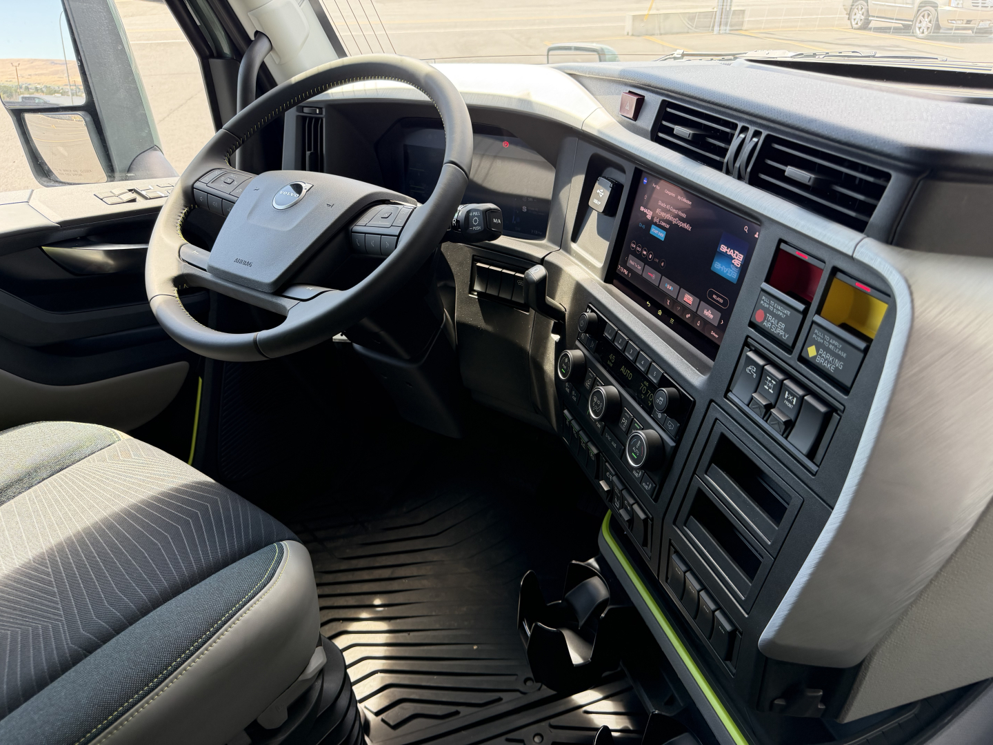 Volvo VNL64T860 truck interior showing steering wheel, dashboard with touchscreen infotainment, climate controls, and driver seat in view.