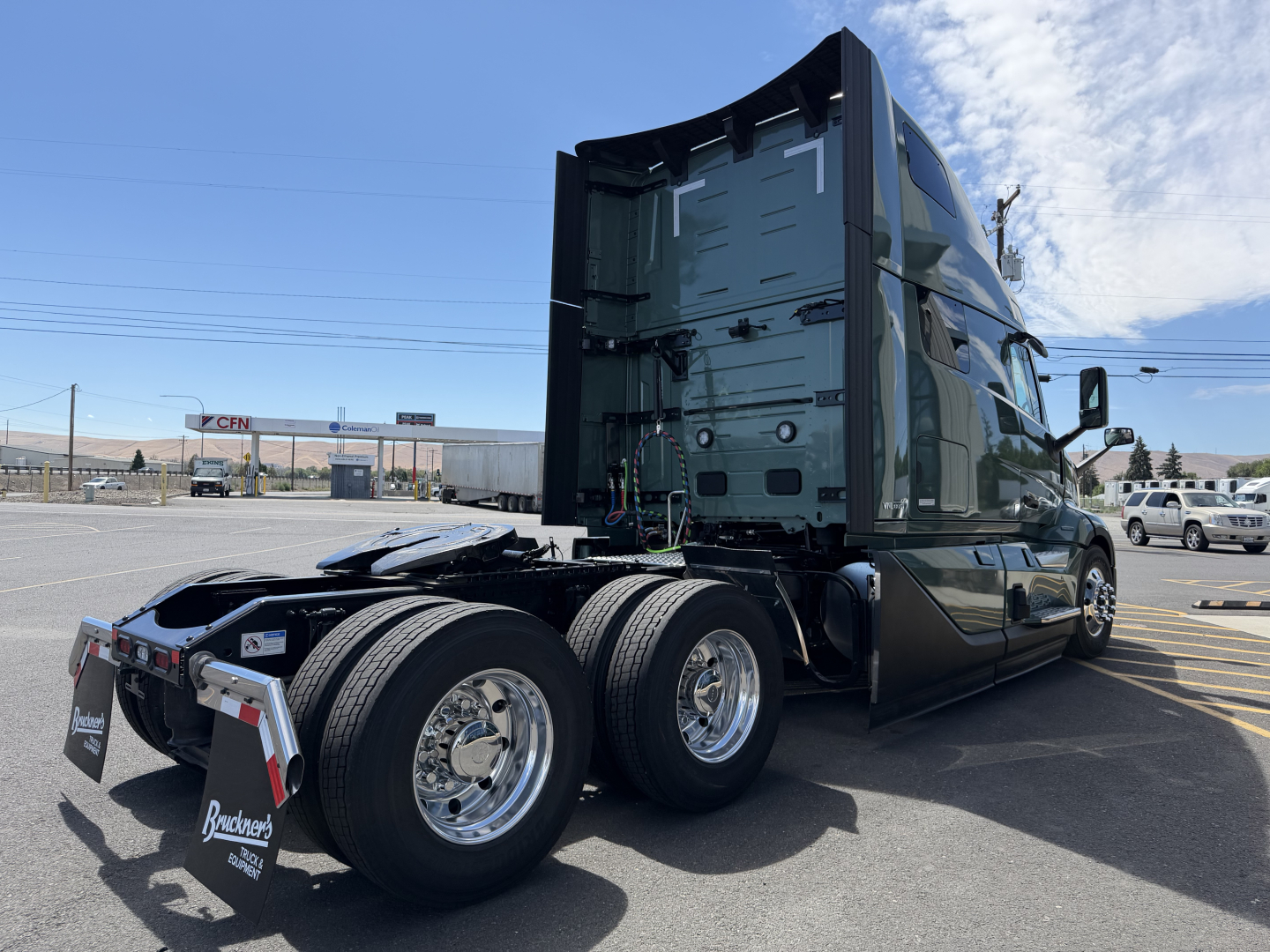 Volvo VNL64T860 tractor chassis rear/side view showing dual rear axles and sleeper cab, green paint, chrome wheels, and fifth wheel area visible.