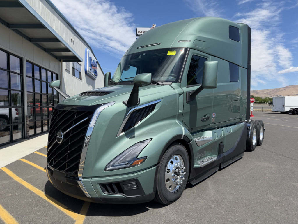 Volvo VNL64T860 truck in green metallic paint shown from front-left angle with sleeper cab. Visible text includes Volvo emblem on grille and side markers; no legible serials or warnings readable from image.