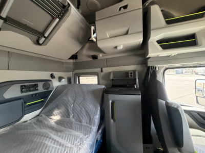 Volvo VNL64T860 truck cab interior showing sleeper berth with protective cover, overhead compartments, and dashboard controls.