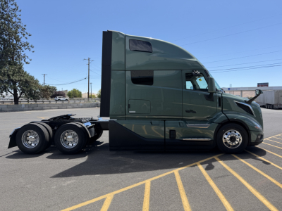 Volvo VNL64T860 semi-truck tractor in green with sleeper cab side view showing 6x4 configuration and dual rear axles.