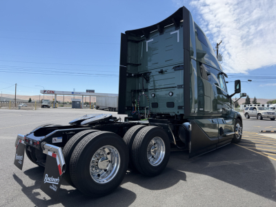 Volvo VNL64T860 tractor chassis rear/side view showing dual rear axles and sleeper cab, green paint, chrome wheels, and fifth wheel area visible.