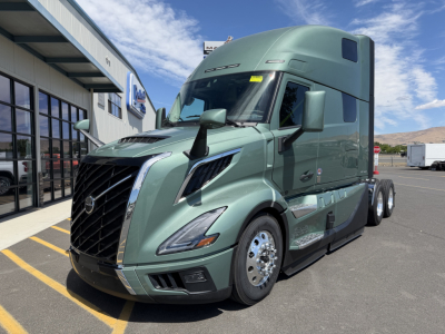 Volvo VNL64T860 truck in green metallic paint shown from front-left angle with sleeper cab. Visible text includes Volvo emblem on grille and side markers; no legible serials or warnings readable from image.