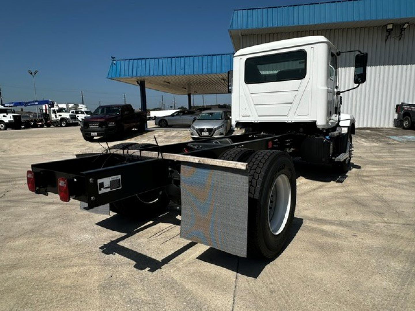 Mack MD6 cab chassis showing rear chassis and rear wheels with aluminum diamond plate fenders and cargo deck.