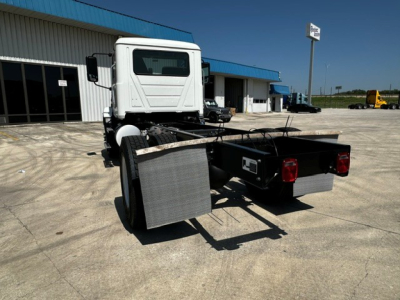 Mack MD6 cab and chassis rear view showing side fenders and dual flatbed mounting, white cab, black chassis, reflecting in bright day.