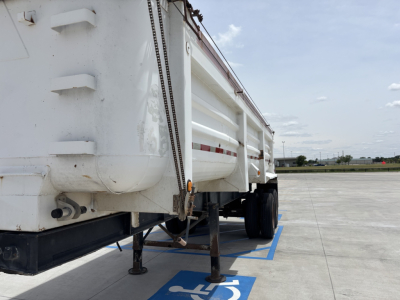 Dump trailer side view showing hydraulic lift and landing gear stabilizers.