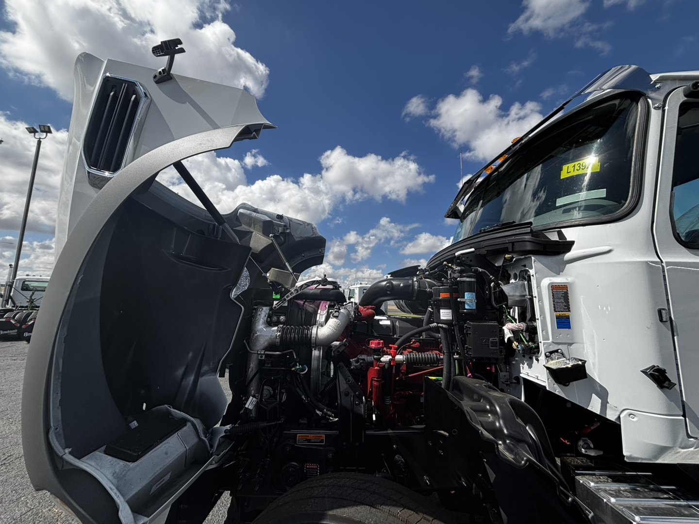 Truck engine bay of a 2027 Mack GR64FT conventional daycab showing exposed engine components and hydraulic lines.