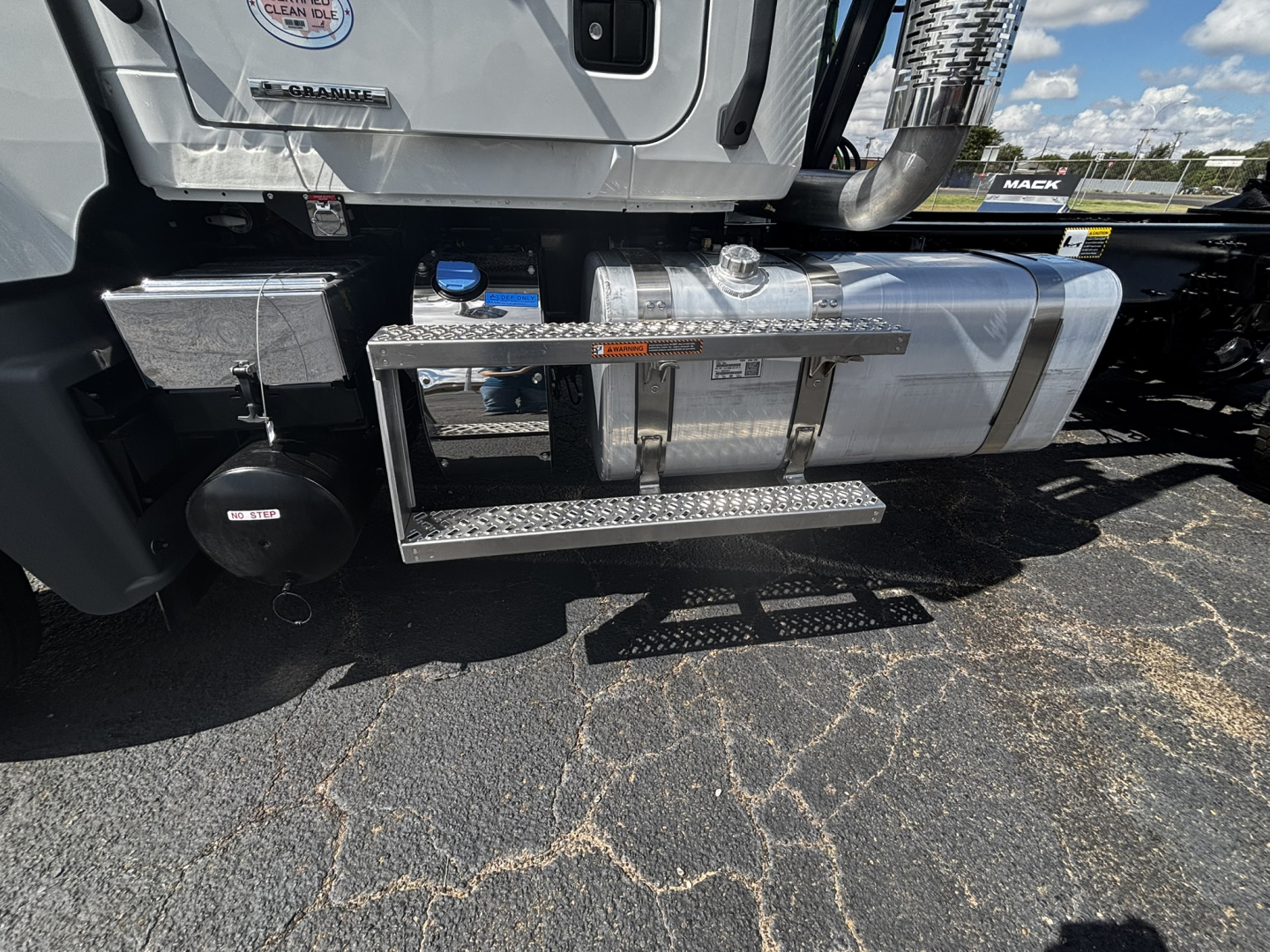 Mack GR64FT cab exterior showing chrome fuel tank and side step, with black circular air reservoir and metal steps.