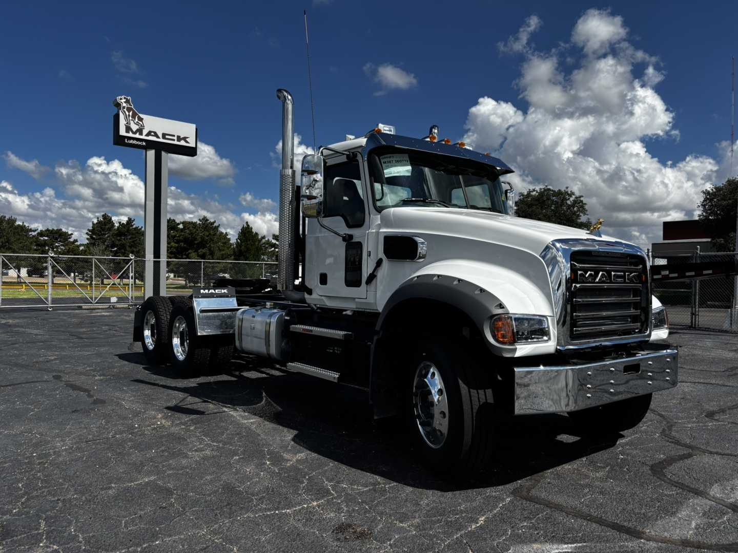 Truck chassis and cab in daylight showing Mack GR64FT conventional daycab, hood, grille, and dual rear axles.