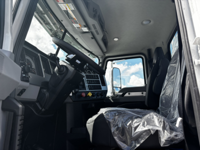 Truck cab interior of a 2027 Mack GR64FT showing steering wheel, dashboard, and driver's seat with plastic cover.
