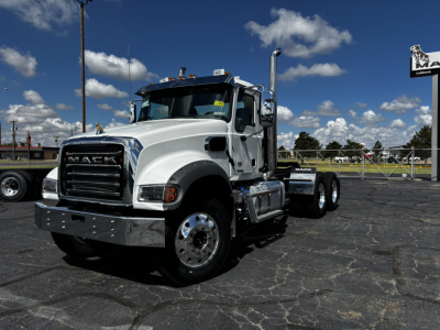 Truck shows front-left view of a white Mack GR64FT conventional daycab with chrome bumper, dual rear axles, and large exhaust stacks; visible text includes 'MACK' on grille.