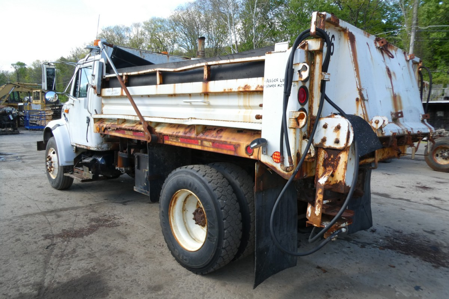 International 4900 dump truck side/rear view showing rusted dump bed and hydraulic lines.