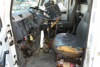 Truck cab interior of a used 1998 International 4900 dump truck showing steering wheel, dashboard, and worn driver's seat.