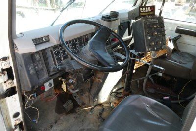 Truck cab interior of an International 4900 showing steering wheel, dashboard, and control module with wiring