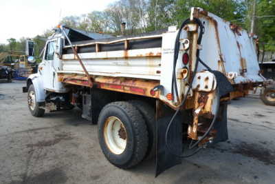 International 4900 dump truck side/rear view showing rusted dump bed and hydraulic lines.