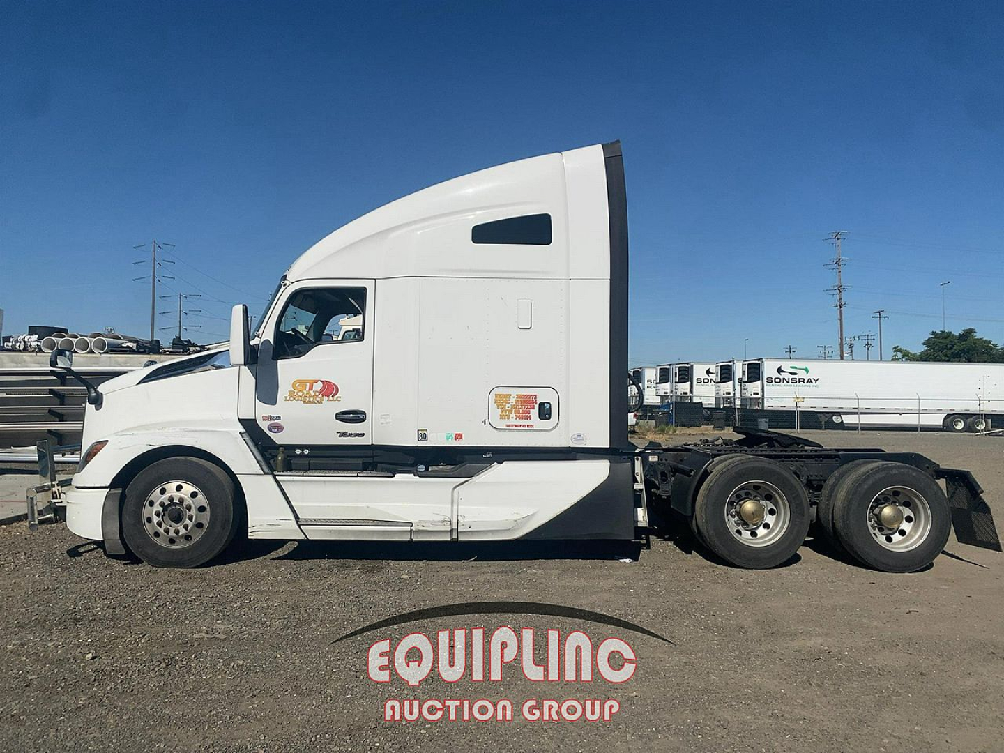 Kenworth T680 tractor tractor with sleeper, side profile, white cab, 6-wheel rear, dealership stickers on door, blue sky.